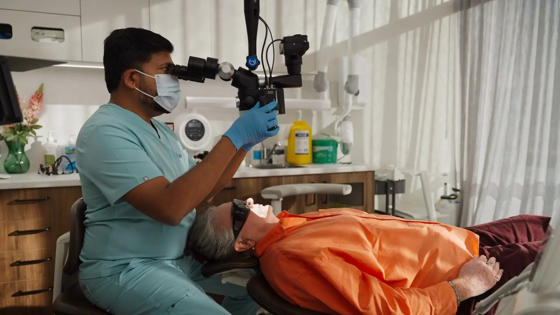 A dentist treating a patient using the dental microscope