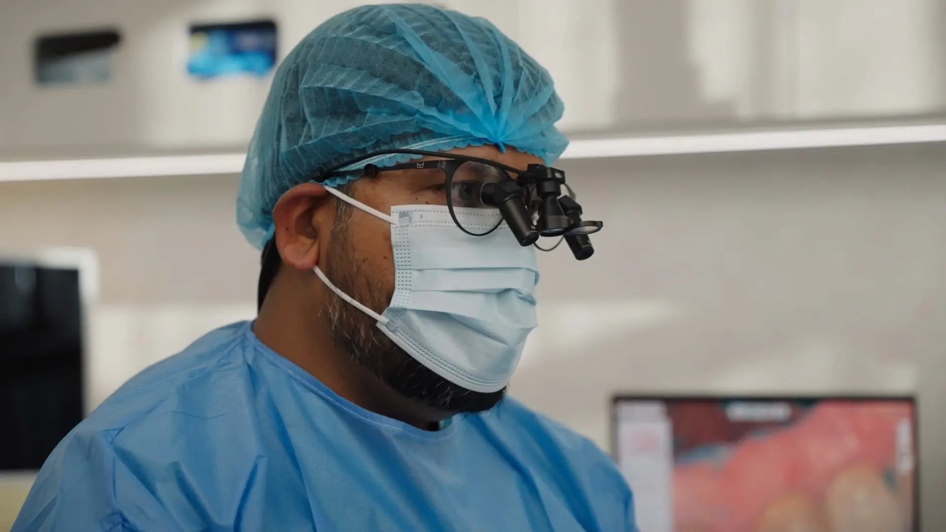 A dentist in a surgical cap and mask